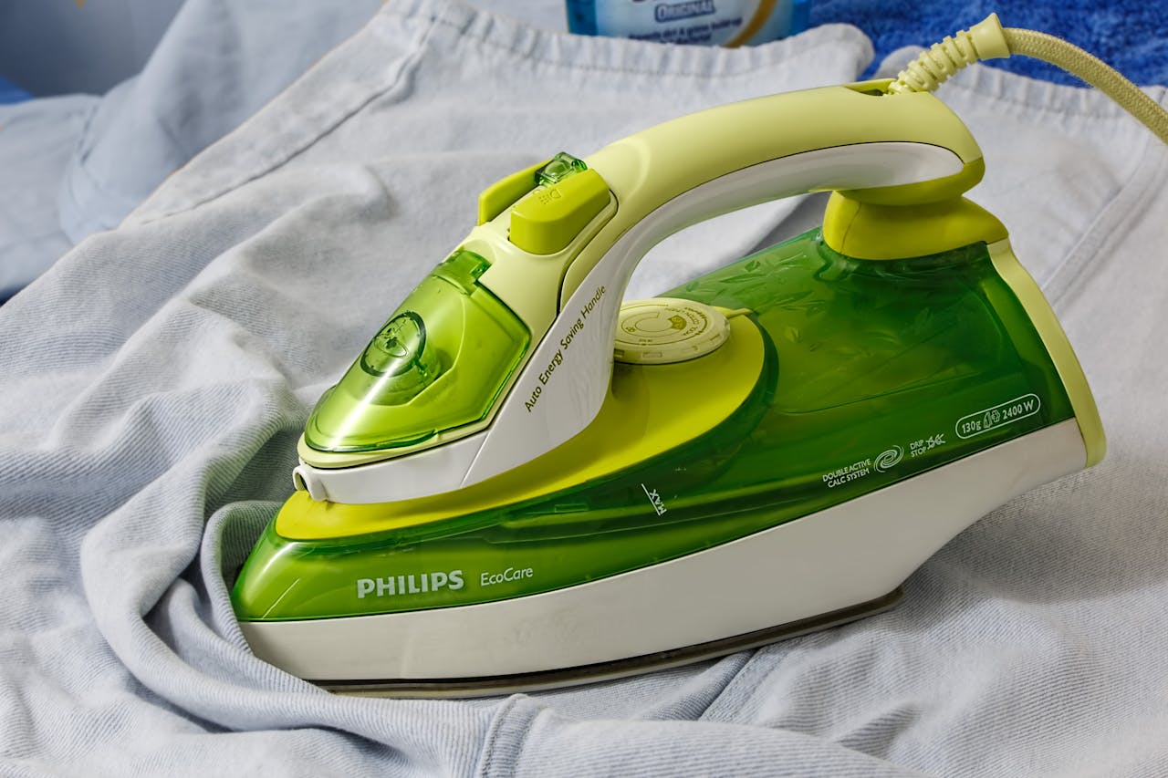 Green Philips EcoCare iron on a wrinkled shirt, ready for ironing.
