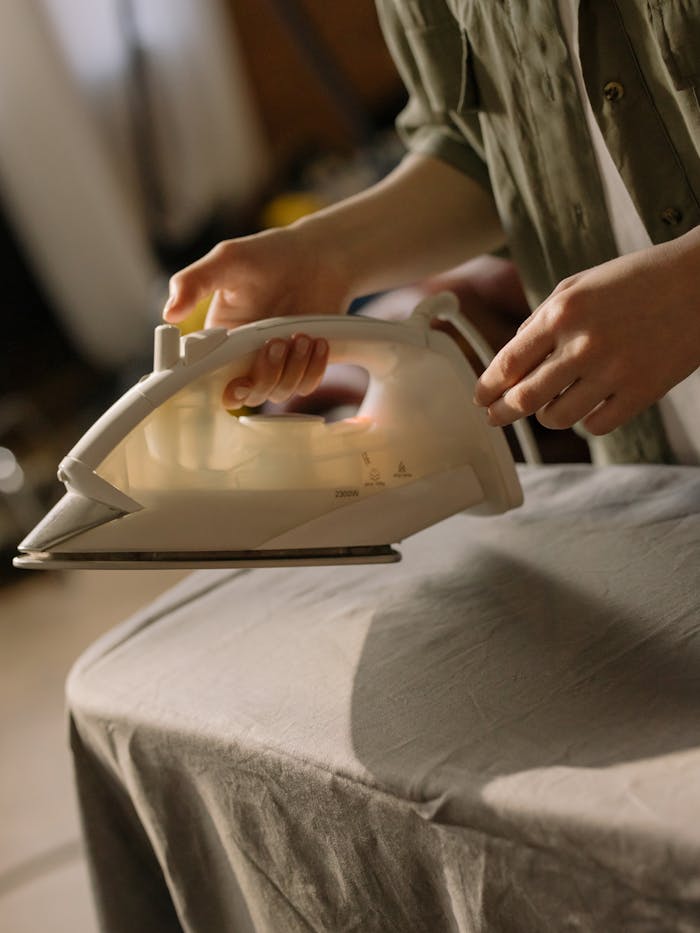 Close-up of a person using an iron on an ironing board, capturing a cozy home setting.