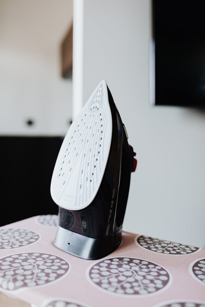 Close-up of a modern clothes iron on an ironing board with a circular pattern, captured indoors.