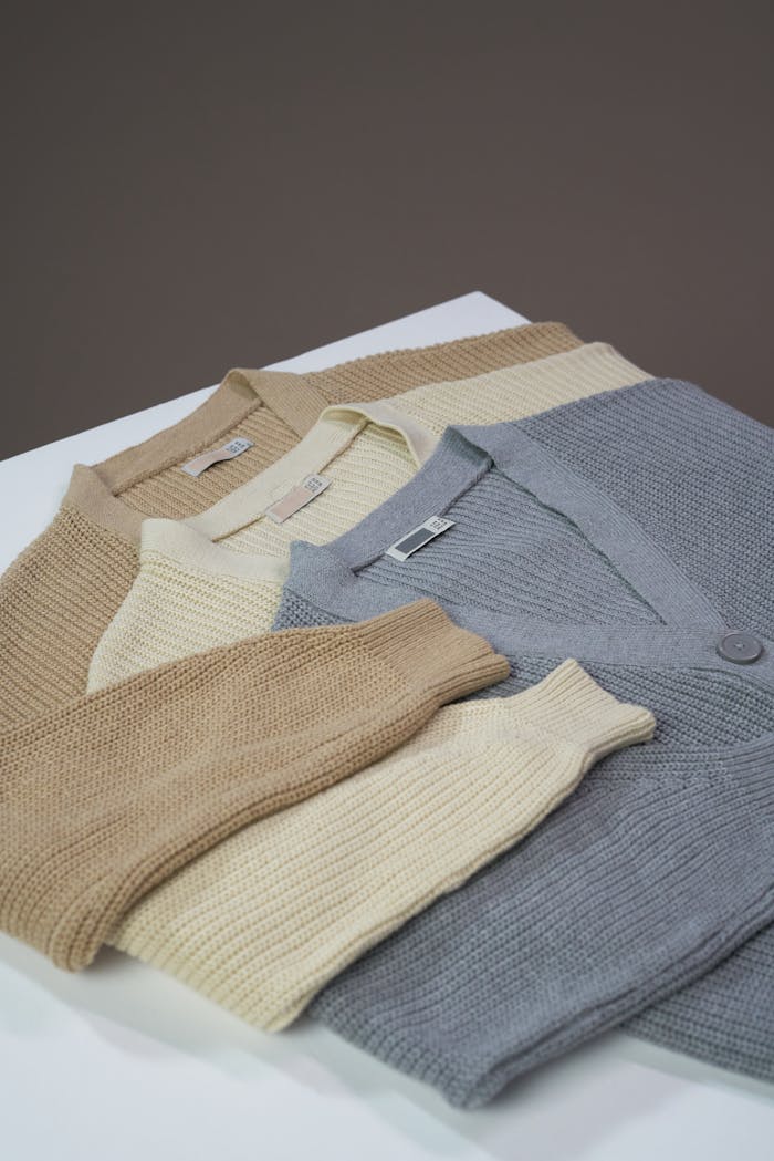 A simple flat lay of neutral-colored cardigan sweaters on a table.